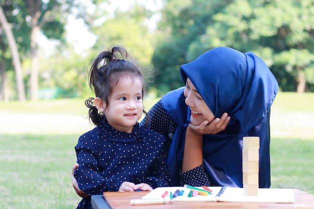 Madre e hija musulmanas disfrutan de relajarse en el parque.