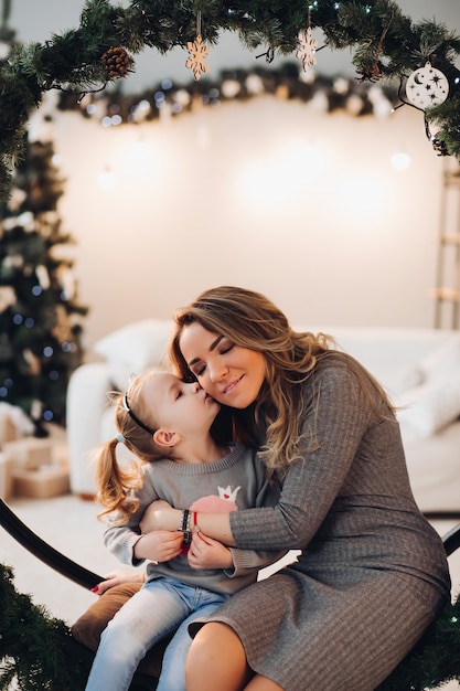 Madre e hija en navidad swing. árbol de navidad.