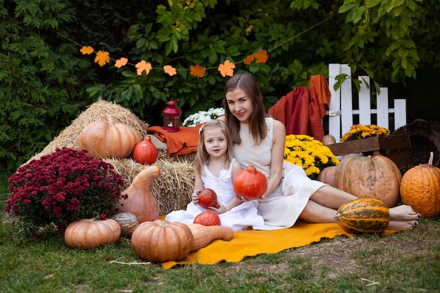 Madre e hija en otoño fondo con calabazas