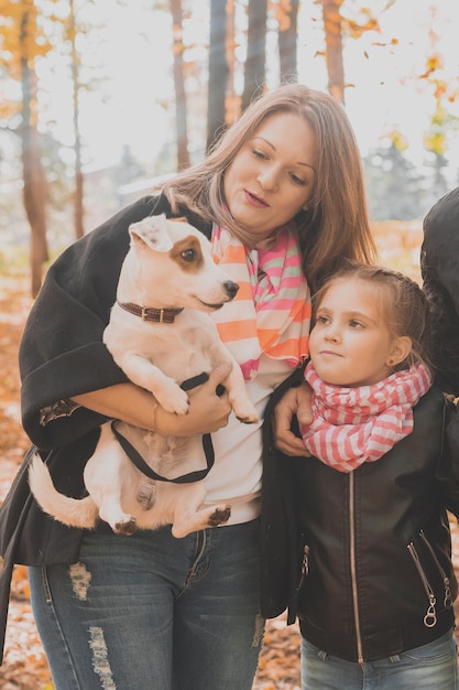 Madre e hija en el parque de otoño niña abrazando a su gato jack russell terrier generaciones de perros mascota y fam