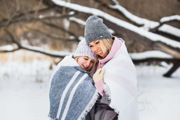 Madre e hija en un paseo de invierno, envuelto en una manta, bosque, campo, invierno