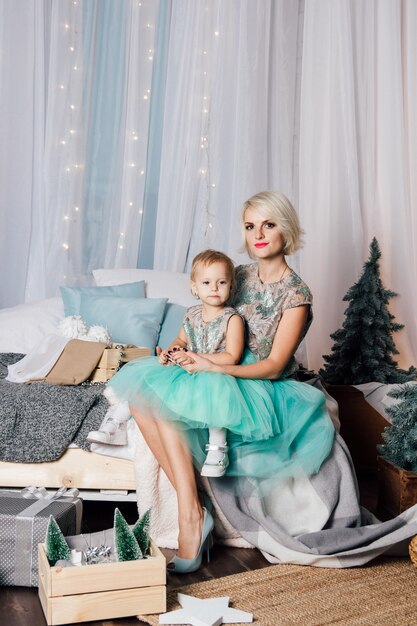 Madre e hija pequeña posando en el interior de año nuevo