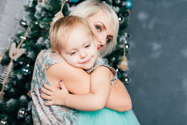 Madre e hija pequeña posando en el interior de año nuevo