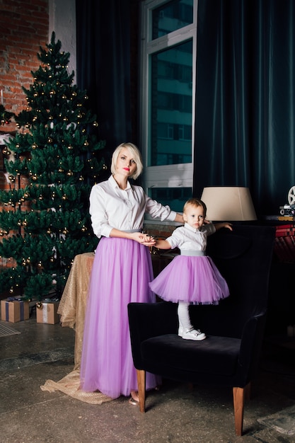 Madre e hija pequeña posando en el interior de año nuevo