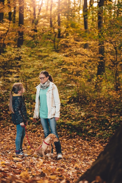 Madre e hija con perro senderismo en un bosque