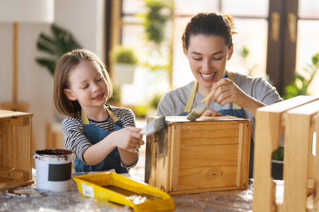 Foto madre e hija pintando una caja de madera