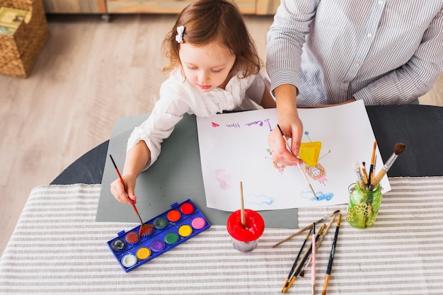 Madre e hija pintando en hoja de papel