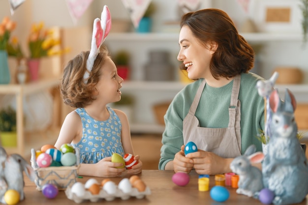 Madre e hija pintando huevos Familia feliz preparándose para la Pascua