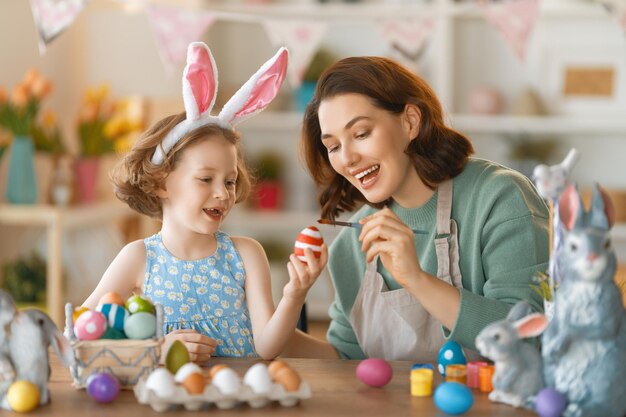 Madre e hija pintando huevos Familia feliz preparándose para la Pascua