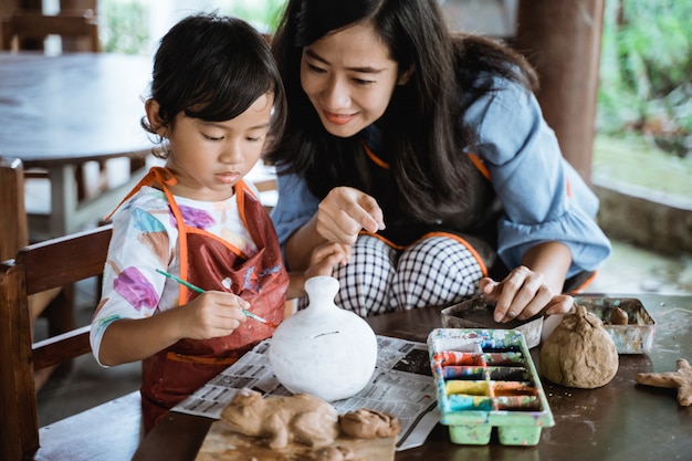 Madre e hija pintando vasija de cerámica