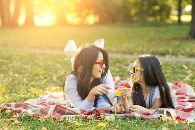 Madre e hija con pompas de jabón en el parque