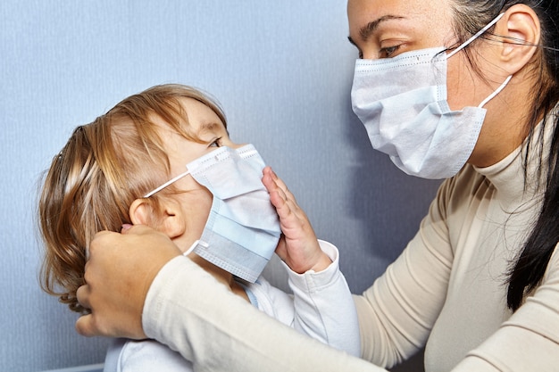 Madre e hija se ponen máscaras médicas en la cara.