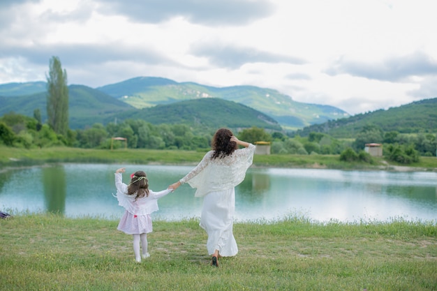 Madre e hija en un prado cerca de un lago de montaña