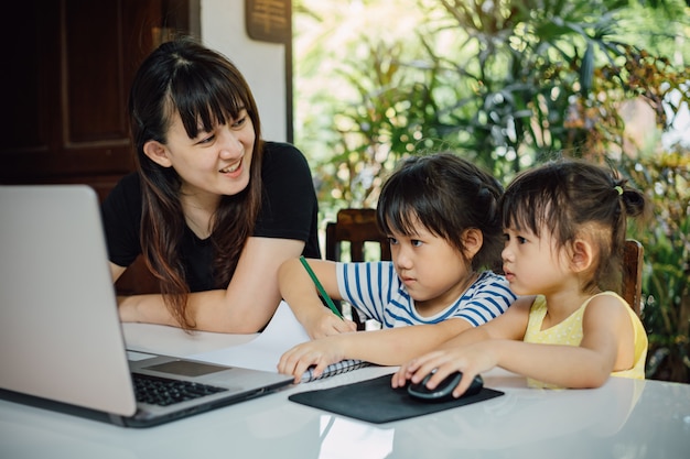 Madre e hija preescolar usando laptop para estudiar en casa.