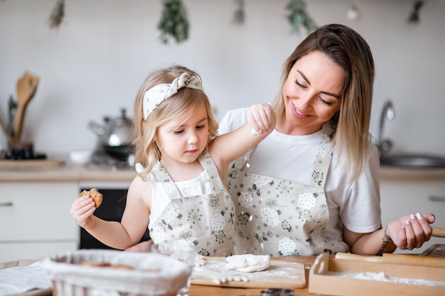 Madre e hija preparan galletas en la cocina en la mesa