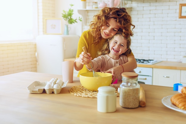 Madre e hija preparan un pastel juntas en la cocina