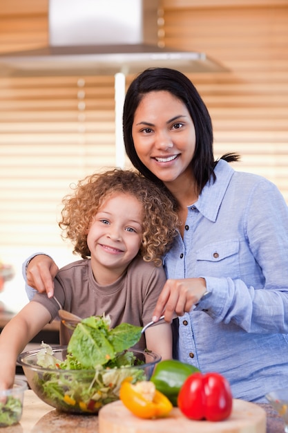 Madre e hija preparando ensalada en la cocina juntos