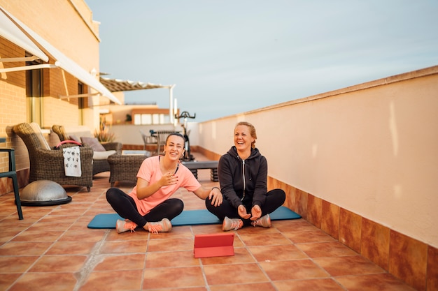 Madre e hija realizan ejercicios de gimnasia en la terraza de su casa