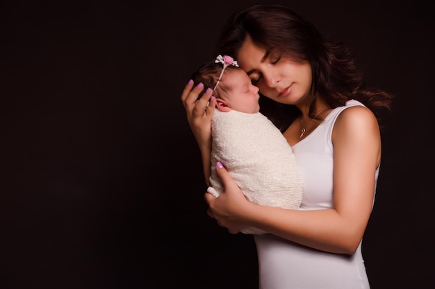 Madre e hija recién nacida sobre fondo negro Madre amorosa y su bebé