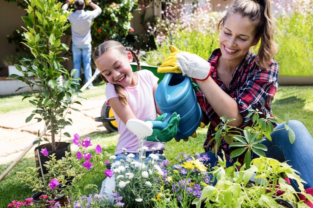 Madre e hija regando las plantas en el jardín