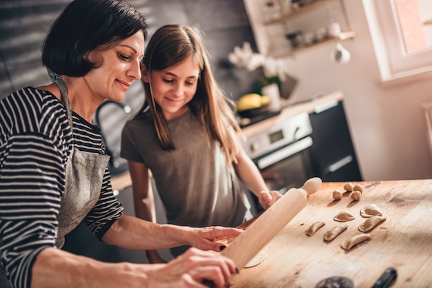 Madre e hija rellenando ravioles con crema de chocolate