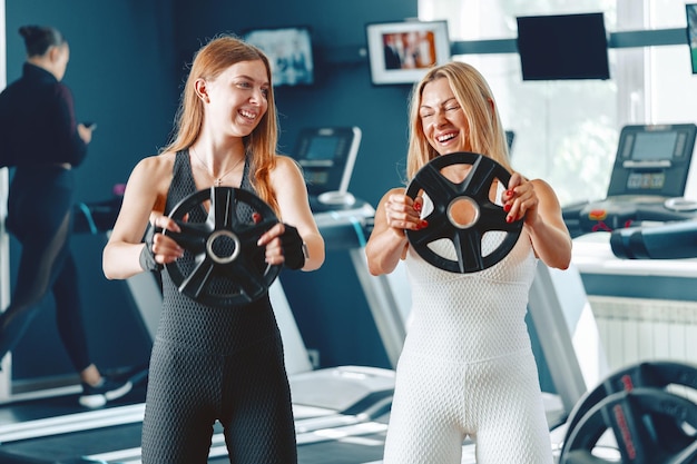 Madre e hija en ropa deportiva haciendo ejercicio con pesas en el gimnasio.