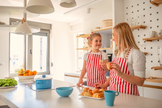 Madre e hija rubia cocinando juntas felizmente