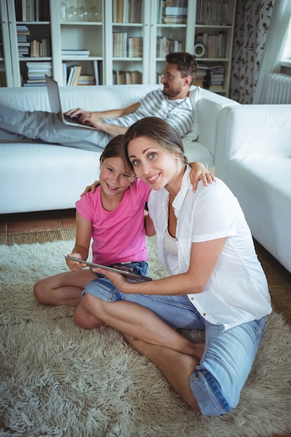 Madre e hija sentada en el piso y usando tableta digital