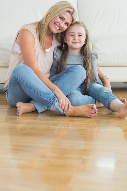 Madre e hija sentada en el suelo abrazando