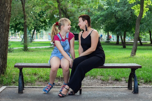 Madre e hija sentadas en un banco en el parque