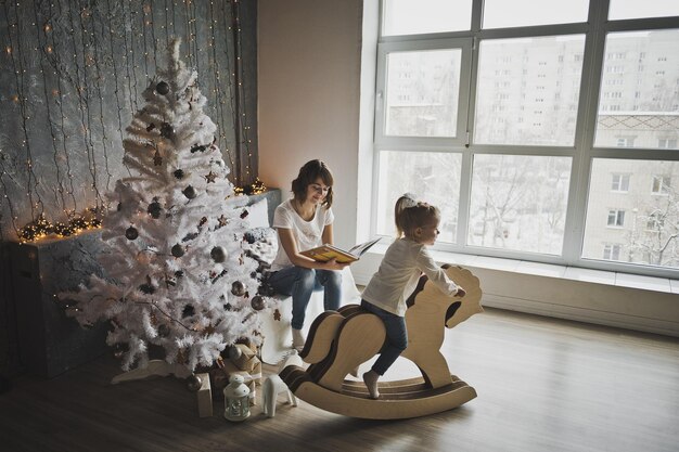 Madre e hija sentadas cerca del árbol de Navidad 7086