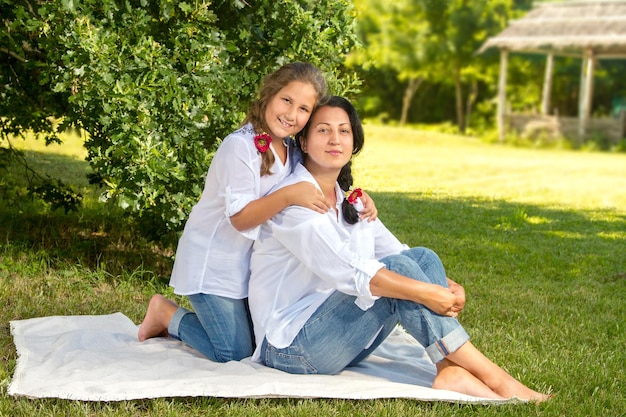 Madre e hija sentadas bajo un roble