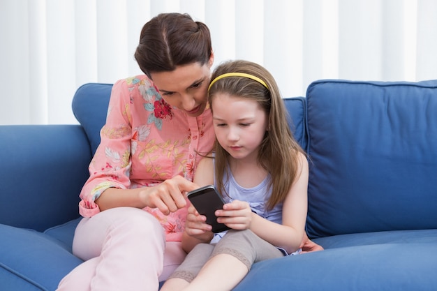 Madre e hija con smartphone en el sofá