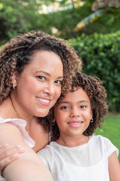 Madre e hija sonriendo y abrazándose en un parque