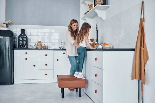 Madre e hija sonriendo mientras preparan algo en la cocina