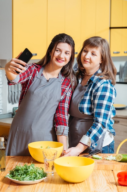 Madre e hija sonriendo y posando en la cocina