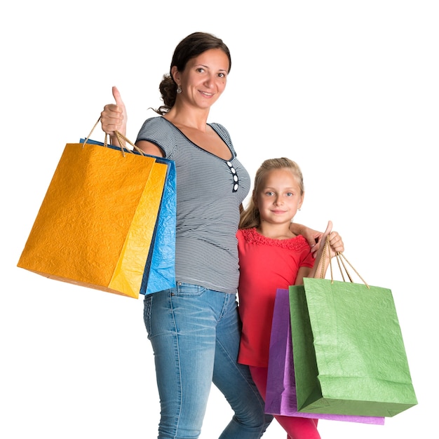 Madre e hija sonriente con bolsas de la compra en una pared blanca.