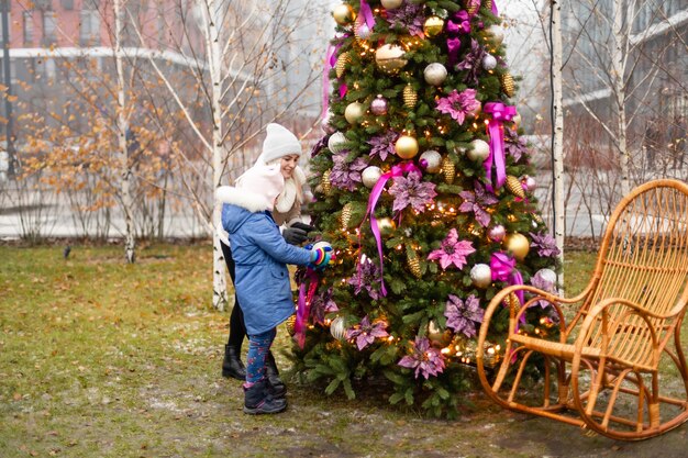 Madre e hija sonrientes cerca del árbol de Navidad