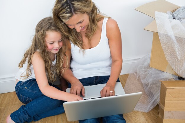 Madre e hija sonrientes que usan la computadora portátil