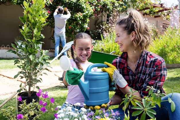 Madre e hija sosteniendo una regadera mientras jardinería