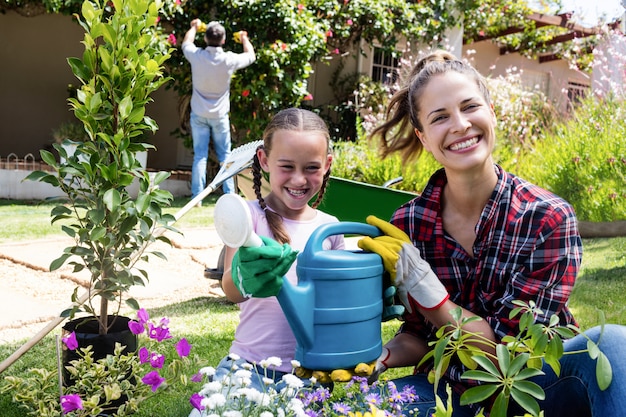 Madre e hija sosteniendo una regadera mientras jardinería