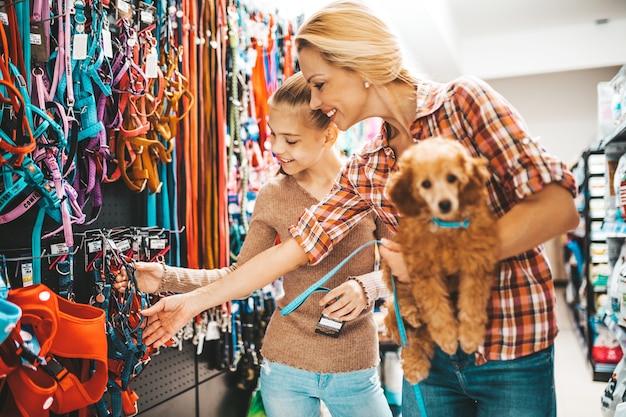 Madre e hija con su cachorro caniche en la tienda de mascotas.