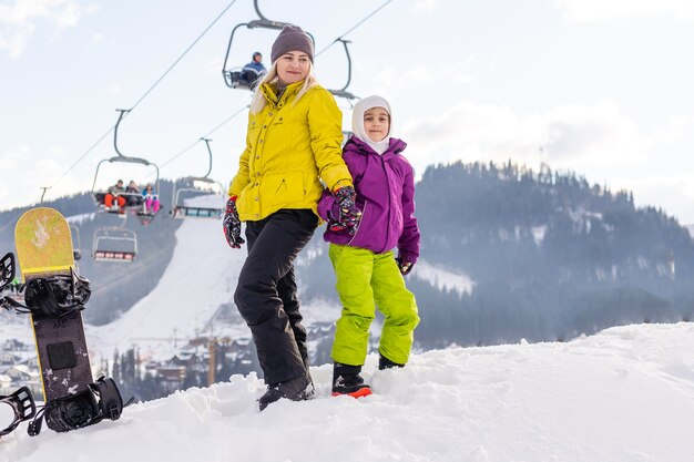 madre e hija con tablas de snowboard en el resort de invierno