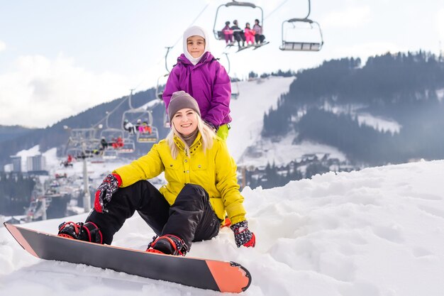 madre e hija con tablas de snowboard en el resort de invierno