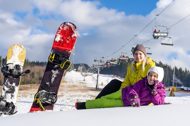 madre e hija con tablas de snowboard en un resort de montaña