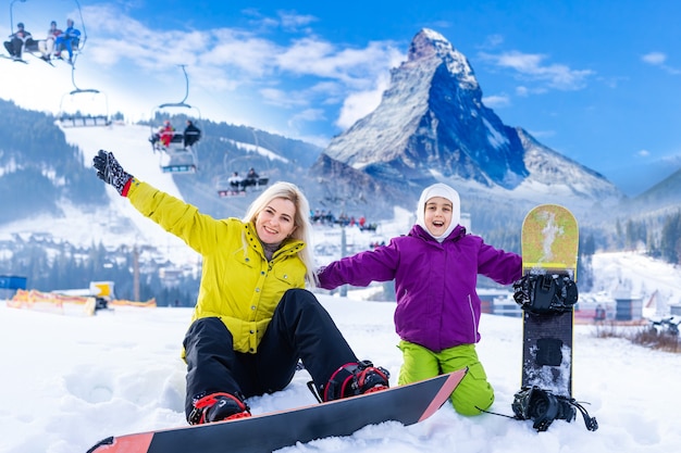 madre e hija con tablas de snowboard en un resort de montaña