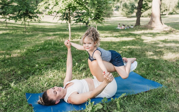 Madre e hija tienen clase de yoga en el parque.