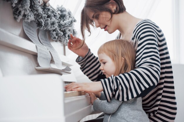 Madre e hija tocando el piano blanco, cerca wiew