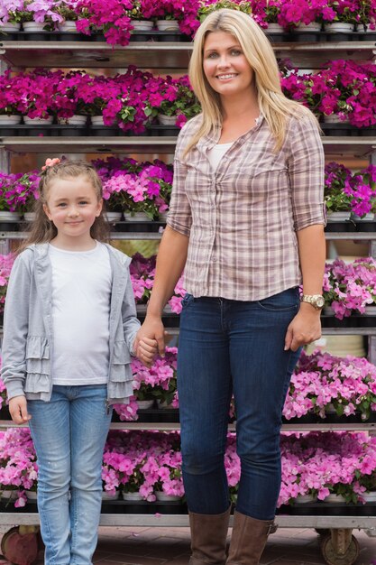 Madre e hija tomados de la mano en el centro de jardinería