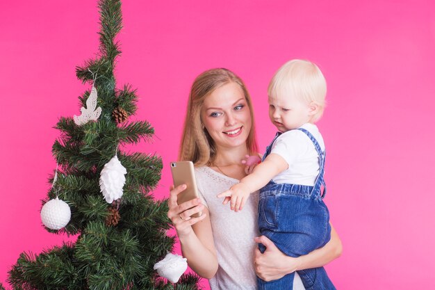 Madre e hija tomando un selfie cerca del árbol de Navidad